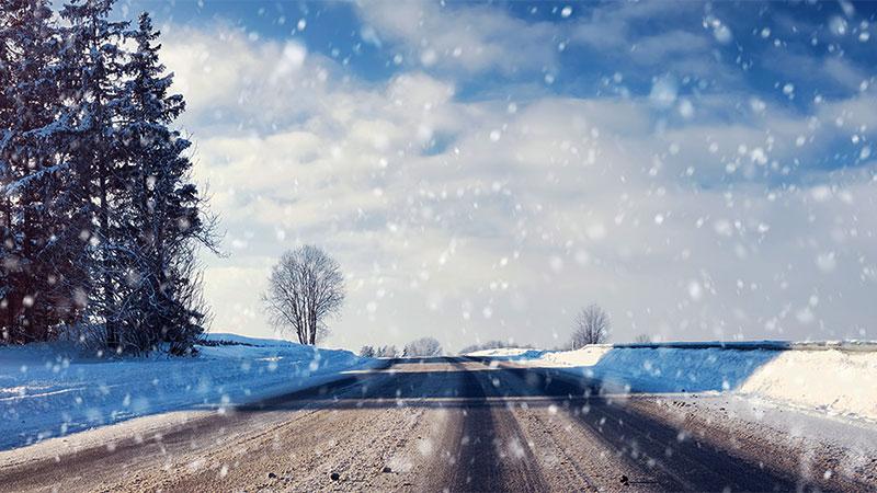 Winter road, sun and snowing